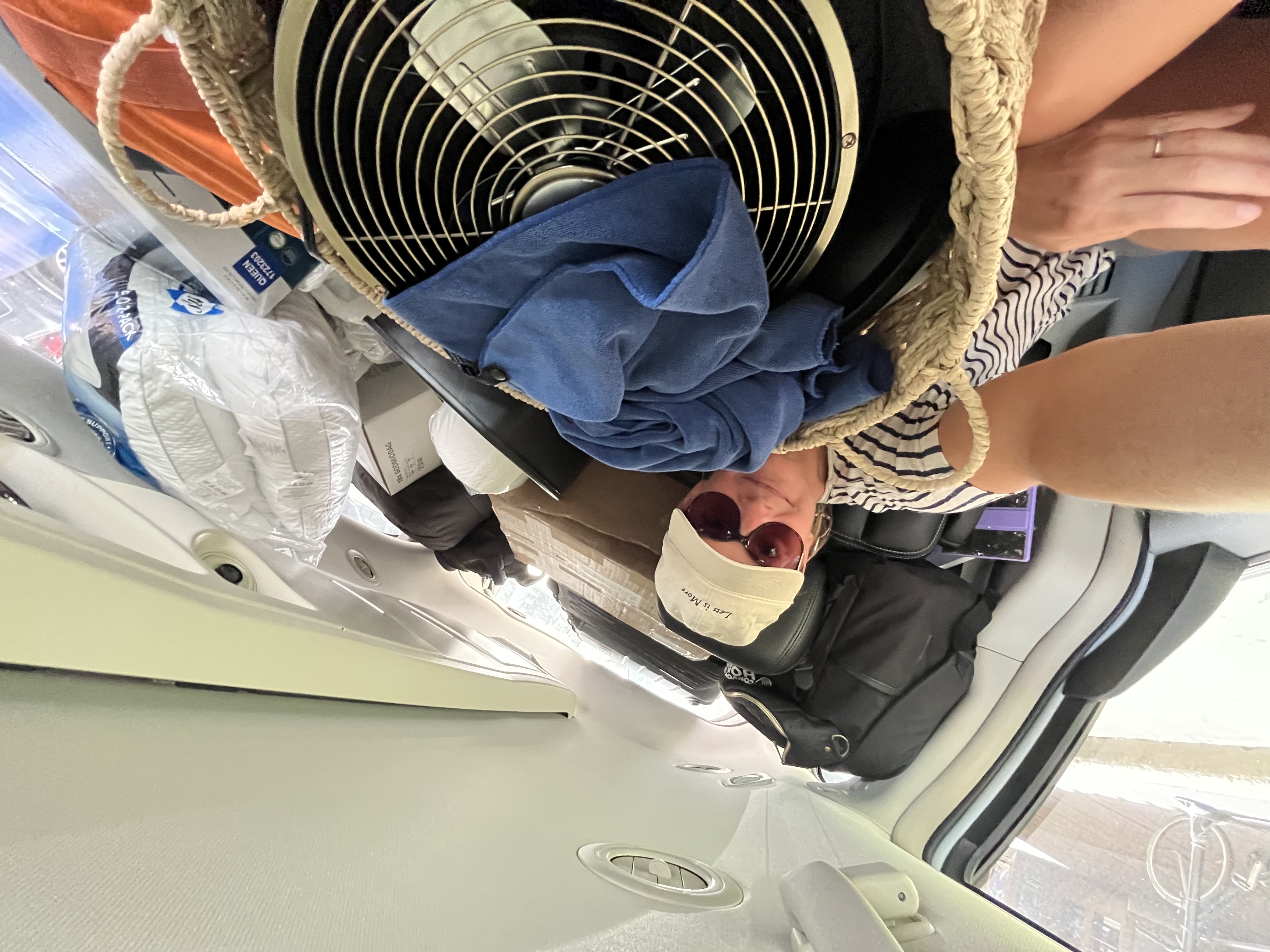 The back of the car packed to the ceiling for moving day: a box fan, bedding, bags and boxes, with Julia tucked in beside it